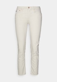 Krémové džíny vyrobené z denimu, s úzkým střihem, designem s pěti kapsami a jemným prošíváním. Zapínání na knoflík a zip vpředu.