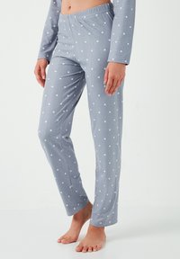 Pantalons de pyjama gris avec des pois blancs, dotés d'une taille élastique et d'une coupe droite, fabriqués dans un tissu doux.
