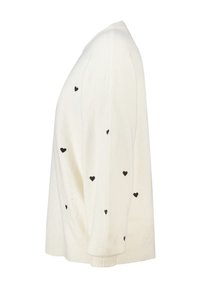 Witte gebreide trui met zwarte hartpatronen, lange mouwen, ribbelboorden en een ontspannen pasvorm. Zachte textuur, casual silhouet.