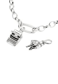Silbernes Gliederarmband mit einer Schreibmaschinen-Anhänger und einem Handzeichen-Anhänger. Beide Anhänger sind detailreich gestaltet und haben ein poliertes Finish.