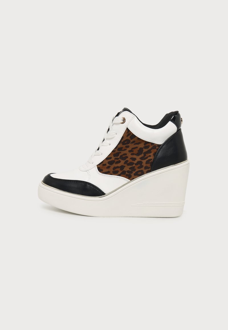 Άσπρο sneakers με σφήνα με μαύρα πάνελ στη μύτη και στη φτέρνα, καφέ λεοπάρ μοτίβο στο πλάι, άσπρα κορδόνια και χοντρή πλατφόρμα στη σόλα.