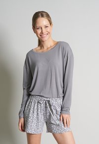 Grijze lange mouw top met een losse pasvorm, gecombineerd met lichtgrijze shorts met een subtiele luipaardprint en een elastische tailleband met een strik.