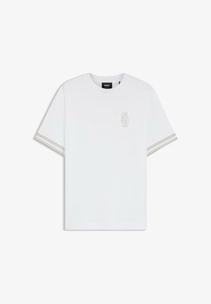 Valkoinen, lyhythihainen T-paita, jossa pyöreä pääntie, pieni brodeerattu "SO"-logo vasemmassa rinnassa ja hihansuissa kaksoisraidallinen reunus.