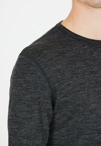 Donkergrijze langwerpige mouwshirt van een gestructureerd, lichtgewicht materiaal met een ronde halslijn en ribbelkant.