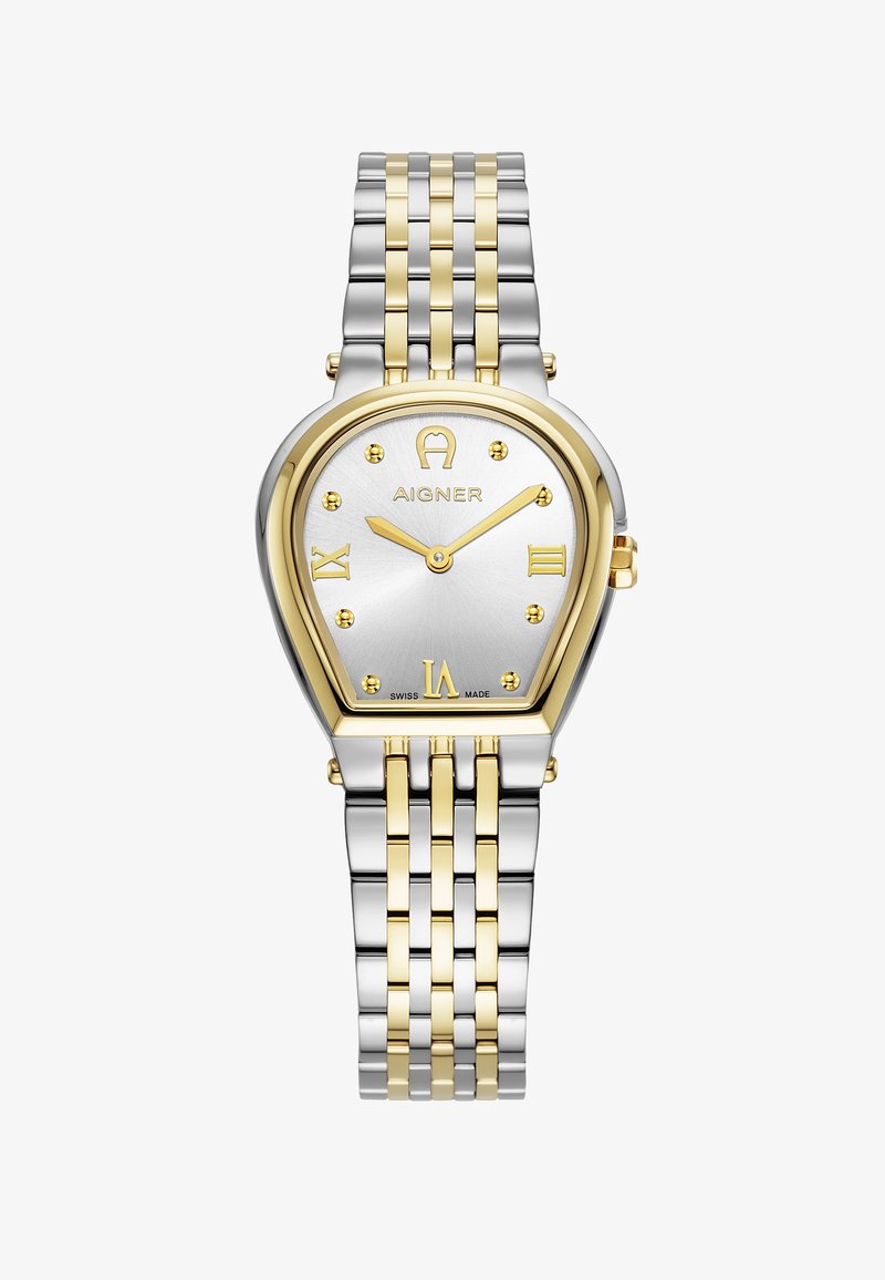 Aukso ir sidabro metalinis laikrodis su ašarėlės forma, sidabriniu ciferblatu, auksiniais romėniškais skaičiais ir tekstūruotu paviršiumi. Įrengtas dviejų spalvų apyranke.