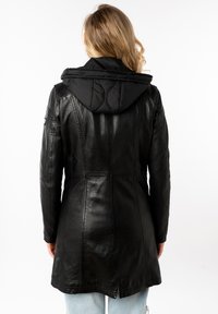 Zwarte leren jas met een gewatteerde zwarte capuchon, getailleerde pasvorm en verticale naden. Voorzien van een kleine rugventilatie voor meer bewegingsvrijheid.