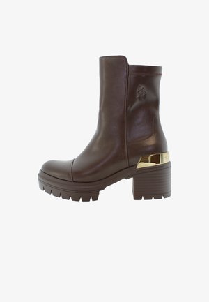 Brun läderankelboot med tjock klack, gummisula och guldaccents. Har en rund tå och subtila sömnadsdetaljer.