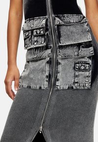 Black ribbed dress with a silver zip closure and gray denim accents, featuring multiple large pockets on the front for added detail.