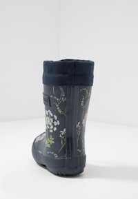 Botte de pluie en caoutchouc à motif floral de couleur bleu foncé, dotée d'un revers en tissu texturé bleu marine, d'une pointe ronde et d'une semelle noire crantée pour une meilleure adhérence.