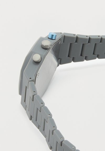 Γκρι ρολόι χειρός με συνδεδεμένο λουράκι, διαθέτει τρία πλευρικά κουμπιά, εκ των οποίων το ένα είναι μεταλλικό μπλε, εμφανιζόμενο από το πλάι και από πίσω.