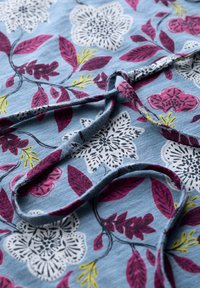 Bloemige katoenen stof met een lichtblauwe achtergrond, met witte en roze bloemen, groene bladeren en een gladde textuur.