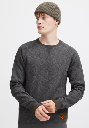 Mørkegrå sweatshirt med rund halsudskæring, ribbede manchetter og et orange logo mærke nær kanten. Stoffet har et struktureret udseende.