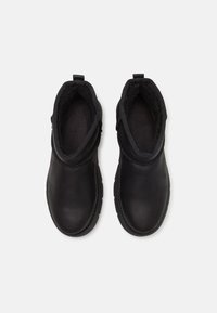 Czarne botki za kostkę z gładkiej skóry, miękką wyściółką, elastycznymi bokami i pętlami do łatwego zakładania.