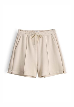 Beige shorts gemaakt van zachte stof, voorzien van een elastische tailleband, een trekkoord met metalen uiteinden en zijzakken. Voorzijde met plooien.