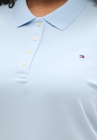 Φωτεινό γαλάζιο πόλο μπλουζάκι από βαμβάκι με κλασικό γιακά και τρία κουμπιά. Διακοσμημένο με μικρό λογότυπο με κόκκινες και ναυτικές ρίγες στο στήθος.