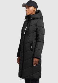 Abrigo acolchado negro con capucha, con cierre de cremallera, diseño de acolchado diagonal, bolsillos laterales y un acento de logo en la parte delantera.