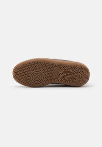Gumi talpú sneaker, kör alakú mintázattal, barna színben és texturált felületű. Könnyű és rugalmas kialakítás.
