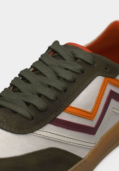 Baskets avec lacets vert foncé, panneaux en daim olive, base blanche, rayures en zigzag orange et bordeaux, et semelle en caoutchouc gomme, vues de côté.