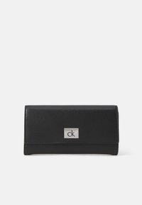Portefeuille en cuir noir avec une finition texturée, présentant une plaque logo "ck" en argent à l'avant, de forme rectangulaire et au design pliable.