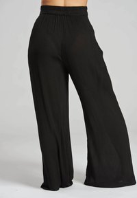 Pantaloni larghi neri realizzati in tessuto testurizzato, caratterizzati da una vita elasticizzata e un design fluido con una vestibilità comoda.