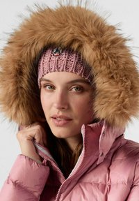 Roze gewatteerde jas met een grote bruine bont gevoerde capuchon en een gebreide roze hoofdband met een logo. Close-up van de kraag en het gezicht.