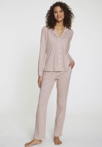 Completo pigiama a maniche lunghe realizzato in tessuto morbido. Presenta una base rosa chiaro con un motivo geometrico in tonalità più scure. Top con bottoni e pantaloni a gamba dritta.