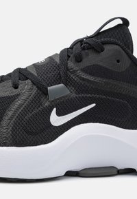 Scarpa sportiva nera con parte superiore in rete tessurizzata, logo Nike swoosh bianco, collo imbottito e suola intermedia bianca ammortizzata.