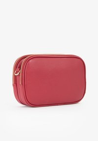 Borsa cosmetica in pelle rossa con forma rettangolare, zip dorata e superficie liscia. Dispone di due scomparti per un'archiviazione organizzata.