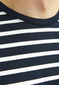 Camiseta de rayas azul marino y blanca con cuello redondo y mangas cortas. Confeccionada en suave algodón, presenta una textura lisa y rayas uniformes.