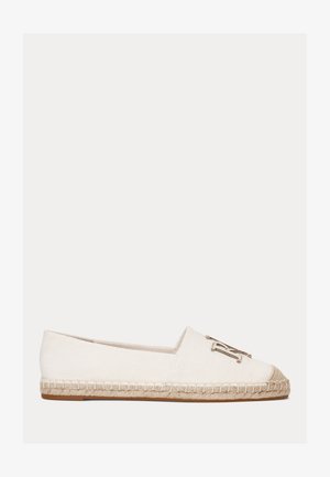 Witte canvas platte espadrille met een gevlochten juten zool en een metalen sierembleem aan de bovenkant vooraan.