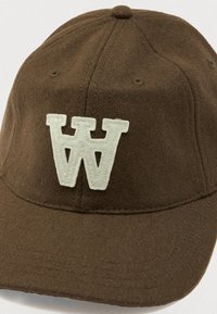 Brown felt cap with a curved brim, featuring a cream-colored "W" embroidered on the front. Textured surface with visible stitching details.