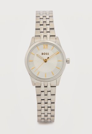 Srebrny zegarek na rękę z metalową bransoletą, białą tarczą, złotymi znacznikami godzin, w tym rzymską cyfrą XII, oraz logo BOSS na środku.