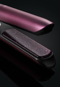 Haardroger met een textuur in fuchsia, zwarte accenten en een glanzende keramische plaat. Platte randen en een slank ontwerp.
