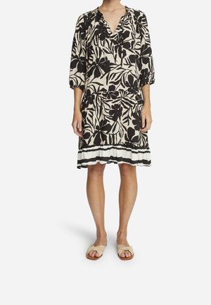 Black and cream floral dress with a V-neck, three-quarter sleeves, and a gathered waist, featuring a layered hem with white accents.