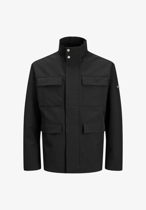 Crna jakna s visokim ovratnikom, dva velika prednja džepa i zatvaranjem sprijeda. Napravljena od glatkog materijala s minimalnim detaljima.