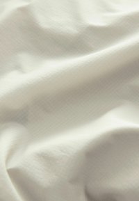 White textured fabric with a subtle grid pattern, featuring soft drapes and a smooth surface. Ideal for various textile applications.