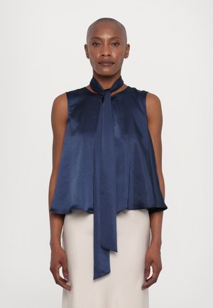 Navyblauw satijnen mouwloos topje met een vloeiende silhouet en een lange strik bij de hals. Gladde textuur met een ronde halslijn en een uitlopende zoom.