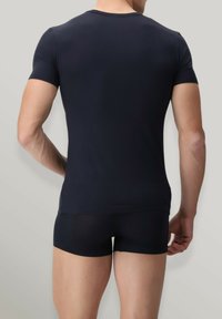 Maglietta nera a maniche corte aderente realizzata in materiale elastico, abbinata a pantaloni corti neri attillati. Tessuto liscio, design minimalista, senza motivi visibili.