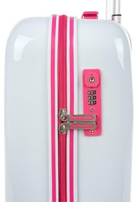 Maleta rígida blanca con cremallera rosa y acentos, cremalleras dobles y un candado de combinación. Textura suave y diseño moderno.