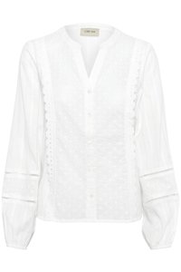 Vit blus med knappar som har broderie anglaise-detaljer, en placket-hals, och puffärmar med elastiska ärmslut. Mjuk tygtextur.