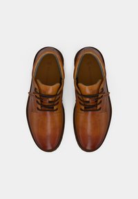 Scarpe stringate in pelle marrone con finitura liscia, punta rotonda, suola scura in contrasto e dettaglio di cucitura sottile sulla tomaia.