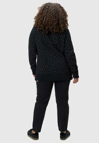 Felpa nera con piccoli motivi colorati sul tessuto, abbinata a jeans scuri e sneakers nere, con polsini e orlo a coste.