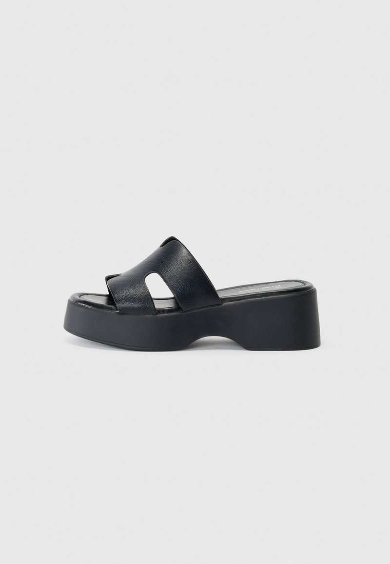Sandalias de plataforma negras con dos tiras entrecruzadas, parte superior de cuero texturizado y suela de espuma contorneada para mayor comodidad.