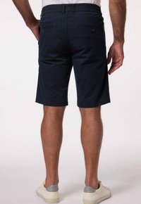 Námorně modré bavlněné kraťasy s rovný střih a dvouma zadníma kapsama, s hladkým texturem a jednoduchým designem. Nosí se s bílými teniskami.