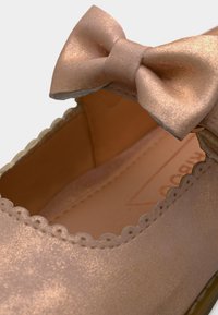 Sädelev roosa kulla toonis baleriinasuss laineliste äärte ja eesosas sobiva paelakesega.