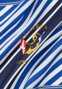 Υφασμα με μπλε και άσπρες ρίγες, με χρυσή άγκυρα, σκοινί, δύο σημαίες και την επιγραφή «Ralph Lauren» κεντημένη με χρυσά γράμματα.