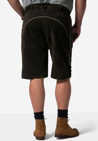 Bruna mockakorts med strukturerad yta, knälånga, med dekorativ sömnad och sidfickor. Bärs med bruna stövlar och mörka strumpor.