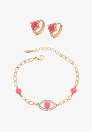 Gouden armband met roze stenen en een oogvormige hanger, gecombineerd met gouden oorringen met roze diamantvormige stenen en kleine kristallen.