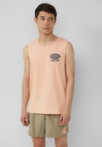 Lichtroze mouwloos topje met het "PACIFIC CUSTOMS" logo in marineblauw, gecombineerd met licht kaki shorts met een klein logo patch.