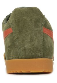 Sneaker verde in suede con striscia laterale arancione, parte superiore testurizzata e suola in gomma. Presenta un tacco arrotondato e dettagli di cucitura visibili.